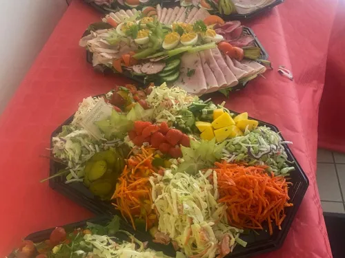 Schotels met vleeswaren, gevulde eitjes en rauwkostsalades op een rood tafelkleed